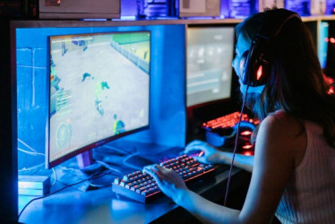 Mujer juega videojuegos en un computador. 