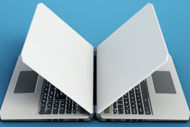 Dos computadores portátiles uno al frente del otro en una superficie azul.