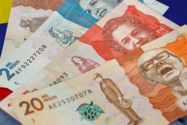 Billetes de pesos colombianos con una bandera de Colombia detrás.