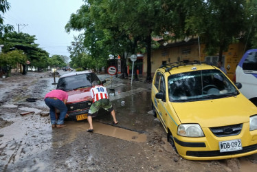 Dos conductores intentan sacar sus vehículos de un agujero que se inundó a raíz de las lluvias registradas en la madrugada de ayer en La Dorada