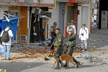Integrantes de la Policía Nacional recorren el lugar donde explotó ayer una motocicleta-bomba en Jamundí (Valle del Cauca).
