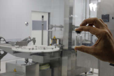 Un hombre sostiene un envase de una vacuna en la planta de producción de vacunas VaxThera