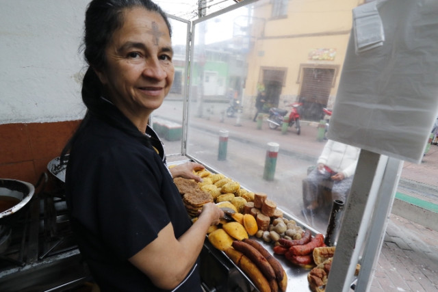 Gloria Gladys Castaño Ossa atiende su puesto de comidas rápidas donde vende empanadas, pasteles de carne y pollo, arepaburguer, chorizo, chicharrón, salchichón, plátano maduro, arepa y arepa con carne desmechada.