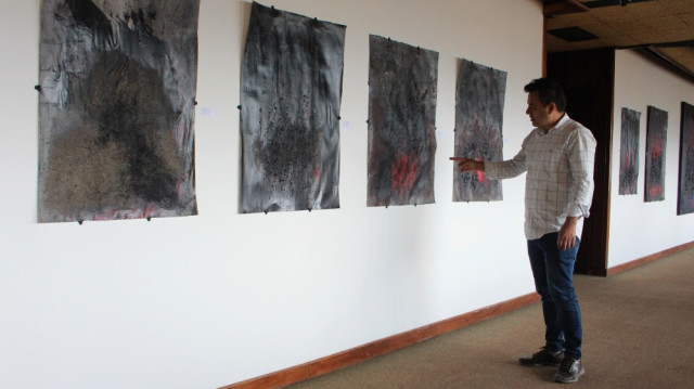 Carlos Fierro Quintero explicando sus cuadros y los nombres de sus obras. Son 16 en total.