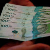 Dos manos sosteniendo billetes de 100 mil pesos Colombianos