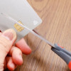 Persona corta una tarjeta de crédito con unas tijeras negras.