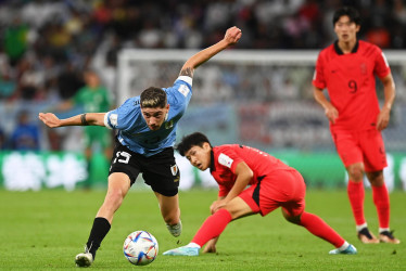 Federico Valverde (i) de Uruguay en acción contra Lee Kang-in (c) de Corea del Sur durante el partido de fútbol del grupo H de la Copa Mundial de la FIFA 2022 entre Uruguay y Corea del Sur en el Education City Stadium en Doha, Catar.