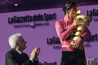 El nuevo ganador del Giro de Italia, el esloveno Primoz Roglic (derecha), besa el trofeo de la competencia, que recibió del presidente italiano, Sergio Mattarella.