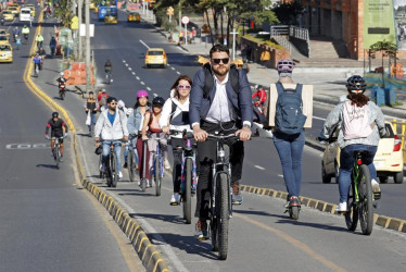 Personas transitan hoy en bicicleta y patineta eléctrica durante el día sin carro, en Bogotá.