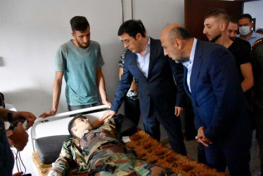 La foto proporcionada por la agencia oficial de noticias árabe siria (SANA) muestra al Ministro de Salud sirio, Hassan al-Ghabash (C), visitando a un herido después de un ataque con aviones no tripulados que tuvo como objetivo una ceremonia de graduación de la academia militar Homs, Siria.