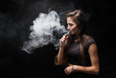 chica-sexy-vestido-negro-fumar-cigarrillo-electronico-pared-oscura