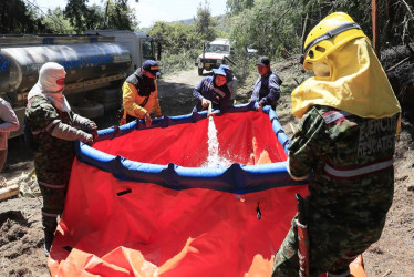 Integrantes de los Bomberos, el Ejército y la Policía llenan una piscina portátil con agua para el combate de un incendio forestal hoy, en Nemocón, municipio cercano a Bogotá (Colombia)