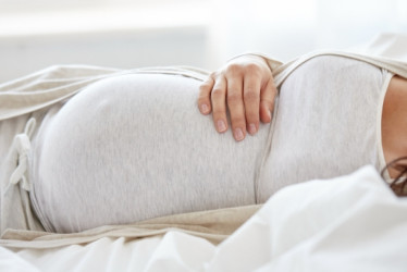 Mujer embarazada acostada en una cama.