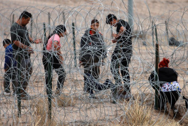 AutoridadeMigrantes intentan cruzar la cerca de alambres en la frontera que divide a México de los Estados Unidos, en Ciudad Juárez (México).s y activistas