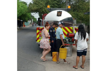 Los ciudadanos con baldes de diversos tamaños arriban al carro de Bomberos para suministrarse de agua.