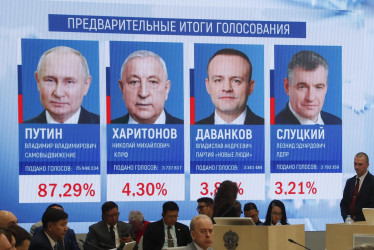 Observadores y periodistas internacionales frente a una pantalla que muestra los resultados preliminares de las elecciones presidenciales en la Comisión Electoral Central en Moscú, Rusia, este lunes.
