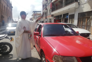 El párroco de La Candelaria bendiciendo un vehículo este Sábado Santo en Riosucio.